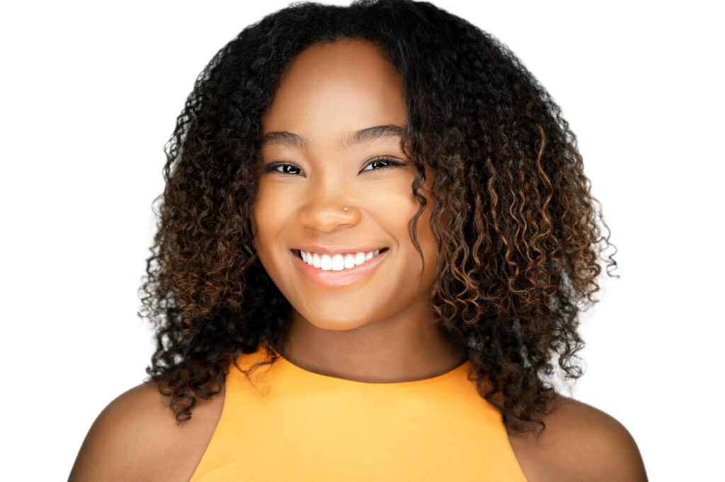 Black young lady with bright smile, yellow top, puffy hair, white backdrop, approachable and vibrant, nyc headshot photographer