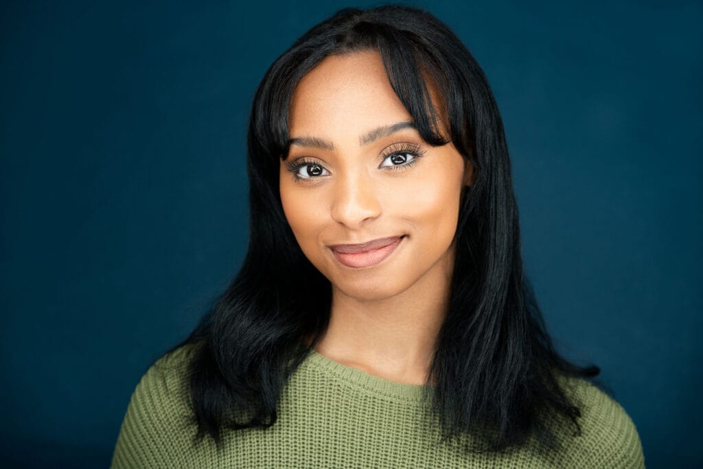 Actress, black hair, dark blue backdrop, green sweater, nice approachable smile, nyc headshot photographer