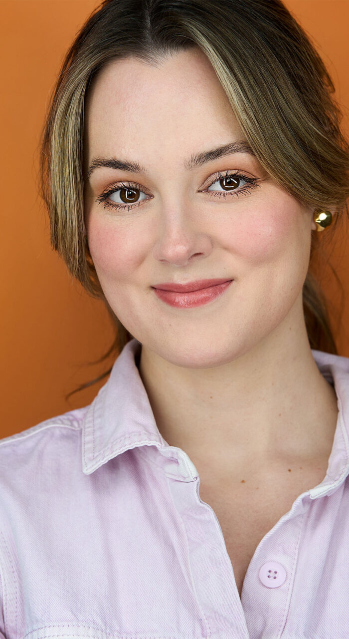 Actress, headshot, no teeth smile, pink jumpsuit, chest high shot, orange backdrop, nyc photographer