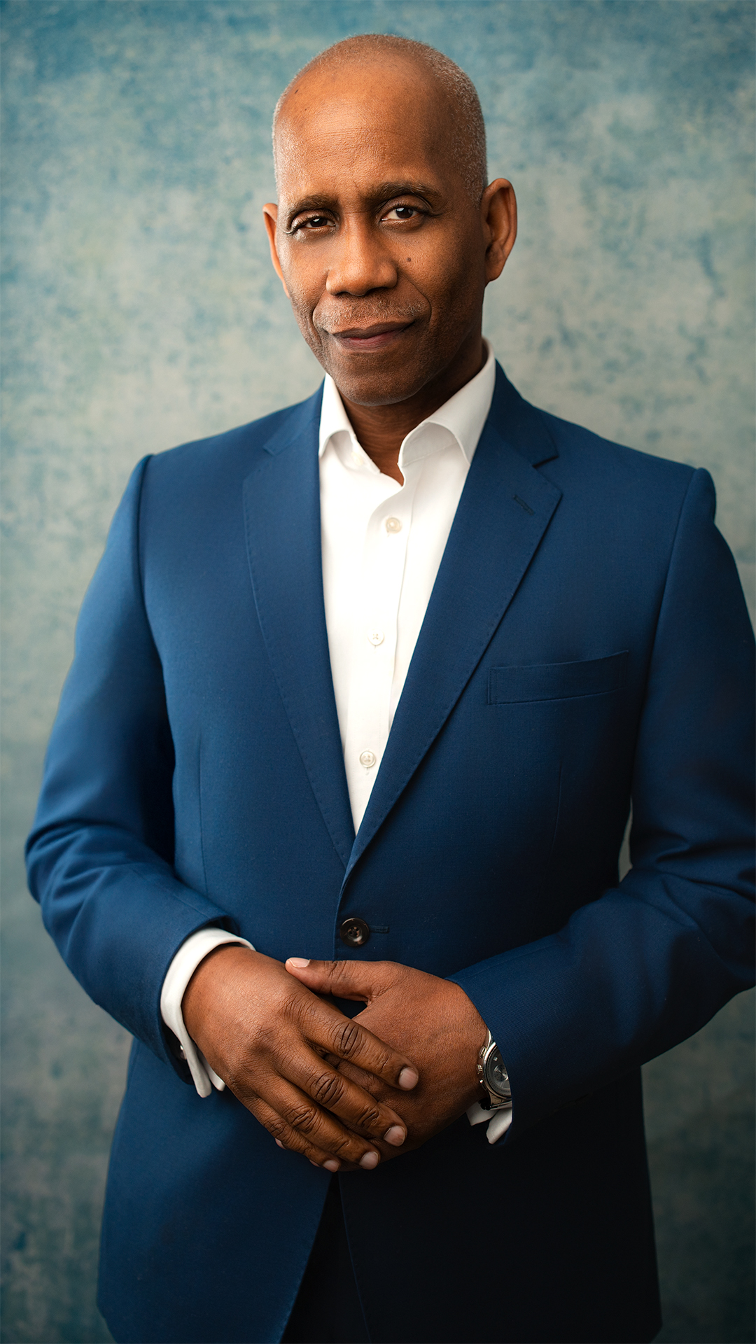 Gentleman in blue suit, no tie, standing looking at camera, portrait