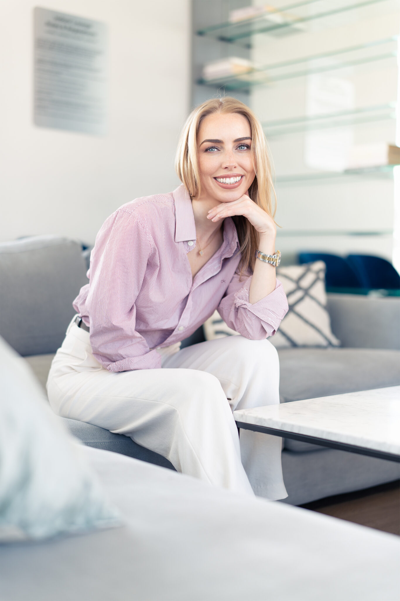 blone blue eye woman sitting on couch looking at camera smiling, nyc portrait