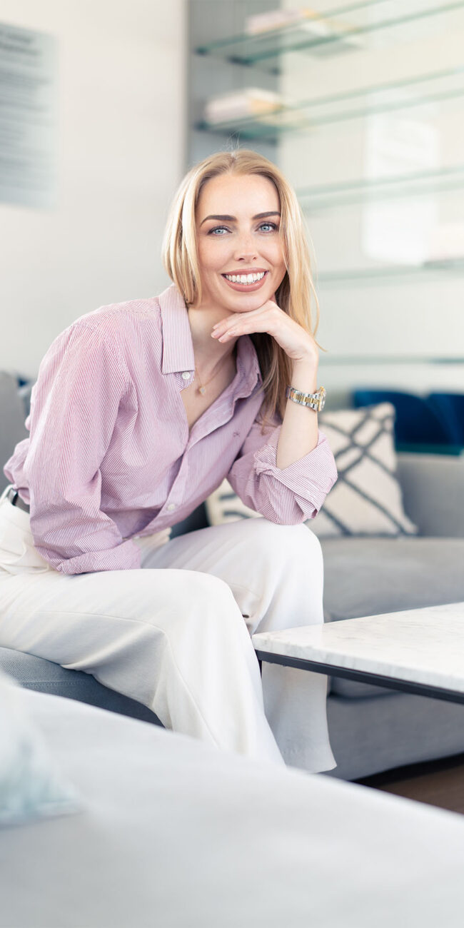 blone blue eye woman sitting on couch looking at camera smiling, nyc portrait
