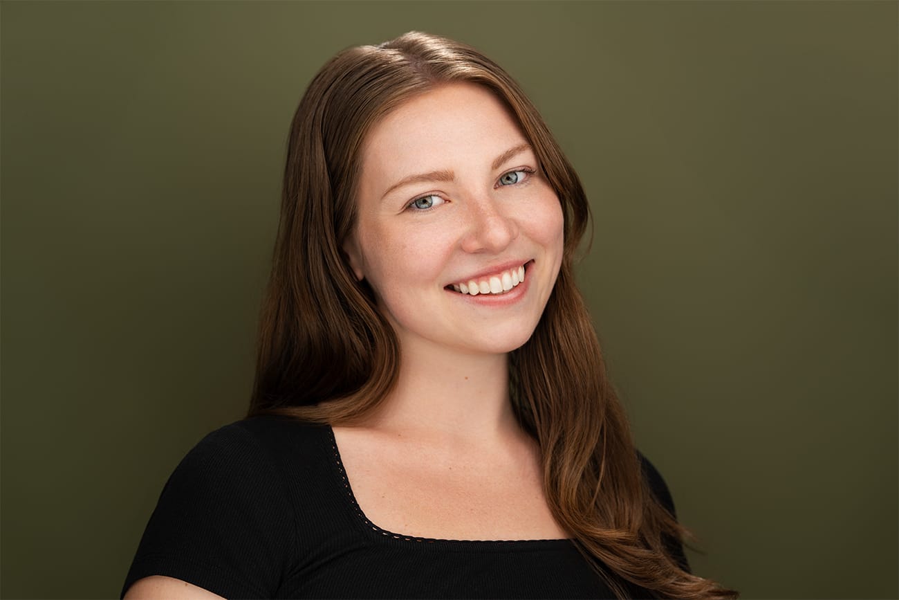 Brunette with smile, black shirt, olive green background, nyc headshot actress
