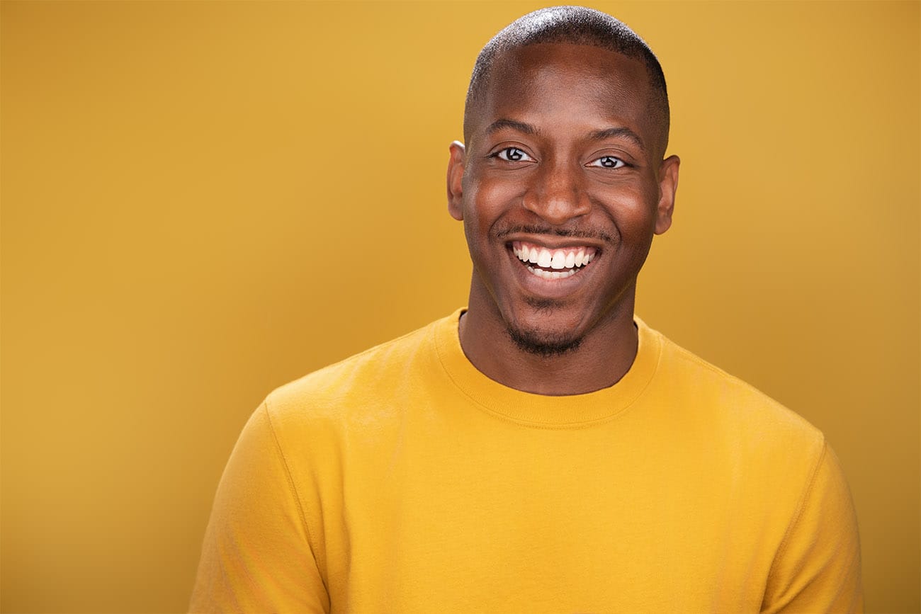 Gentleman with great approachable smile, yellow shirt with match backdrop. NYC Headshot Photographer