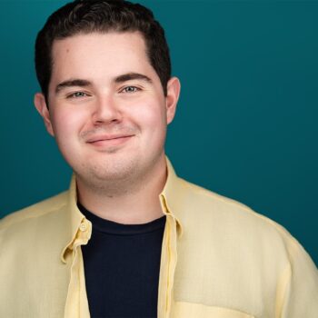 Crisp smile of gentleman with yellow button down shirt opened, blue under shirt, teal backdrop, headshot, nyc headshot photographer