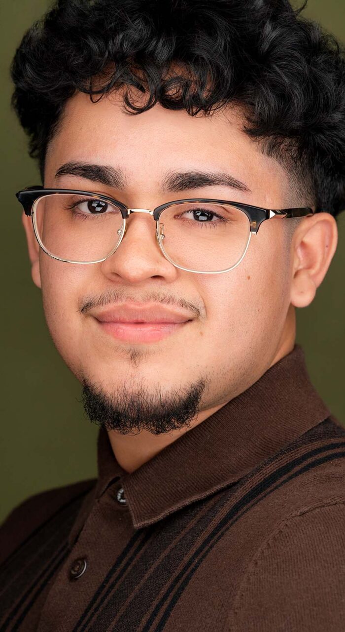 Actor headshot of Daniel Menjivar wearing glasses against green